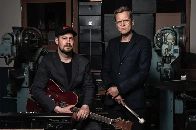 Pressebillede af Emil de Waal og Gustaf Ljunggren med guitar og trommestikker til koncert.